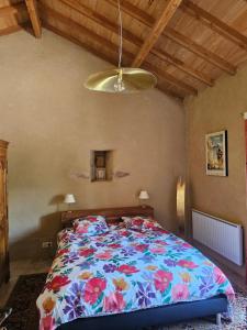 a bedroom with a large bed with a floral bedspread at Entre Pierres et Légendes in Cajarc
