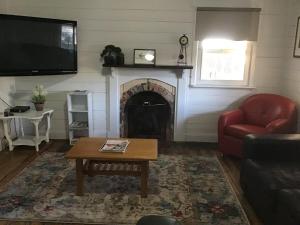 a living room with a fireplace and a red chair at Yallamatta Bed and Breakfast in Apsley