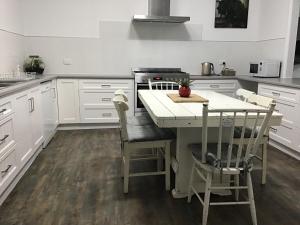 a kitchen with white cabinets and a table and chairs at Yallamatta Bed and Breakfast in Apsley