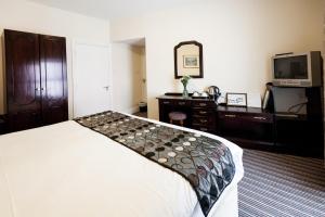 a bedroom with a bed and a dresser and a television at Munster Arms Hotel in Bandon