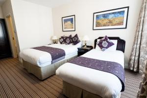 a hotel room with two beds and two lamps at Munster Arms Hotel in Bandon +1 photo