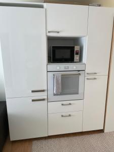 a white kitchen with a microwave and a stove at Gäststuga i mysiga Sparreholm in Sparreholm