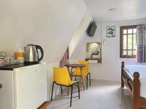 a kitchen with a table and yellow chairs in a room at Pijittra Resort in Uttaradit