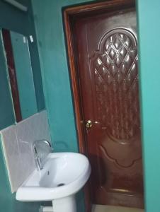 een badkamer met een wastafel en een bruine deur bij Longonot View Camp and Accommodation, Naivasha in Naivasha +32 foto's