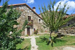 a stone house with a tree in front of it at Casa Rural La Casa de Piedra in Navarredonda de Gredos