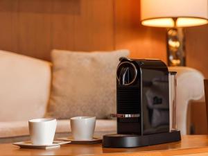 une machine à café posée sur une table avec deux tasses dans l'établissement Chimelong Hengqin Bay Hotel, à Zhuhai