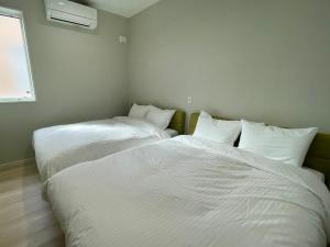 two beds in a room with white sheets and pillows at マール淡路島ラグジュアリービーチリゾート in Awaji