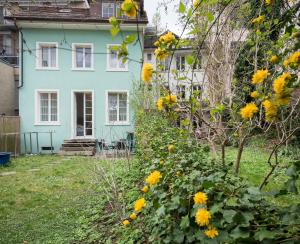 ein blaues Haus mit gelben Blumen im Hof in der Unterkunft EMMA Bett und Bistro in Winterthur