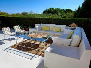 a white couch and chairs on a patio at Casa Junto a la Playa in El Rompido