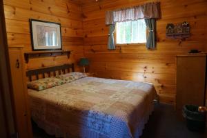 ein Schlafzimmer mit einem Bett in einer Blockhütte in der Unterkunft Meadowview Cottages in North Milton