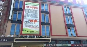 a building with a large sign on the side of it at GreenTree Inn Anhui Suzhou Baima Mall Express Hotel in Suzhou
