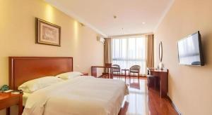 徐州GreenTree Inn Xuzhou High Speed Railway Zhangqian Square Business Hotel的一间卧室，配有一张床、一张书桌和一台电视 更多37张照片
