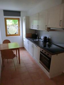 a kitchen with white cabinets and a table and a window at Ferienwohnung Mozart Bayreuth in Bayreuth