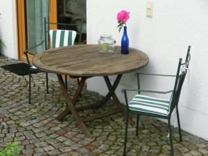 een houten tafel met twee stoelen en een vaas met een bloem bij Ferienwohnung Mozart Bayreuth in Bayreuth