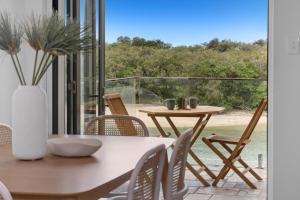 a dining room with a table and chairs and a balcony at Sundaze at Kingy Creek in Kingscliff