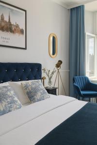 a bedroom with a bed and a blue chair at Staromiejska Panorama -Lokalizacja Premium Widok na Rynek Staromiejski in Toruń