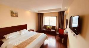 une chambre avec un grand lit et une télévision à écran plat dans l'établissement GreenTree Inn Jiangsu Huaian Bus Terminal North Station Huaihai North Road Business Hotel, à Huai'an