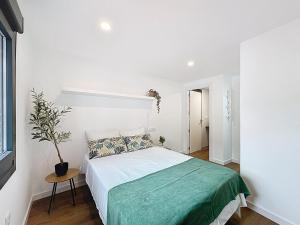 a white bedroom with a bed with a green blanket at Casa PedraMar in O Grove