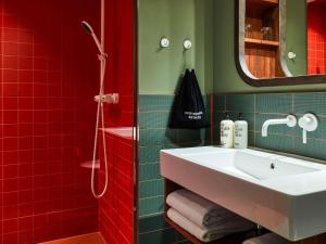 a bathroom with a white sink and red tiles at 25hours Hotel Hamburg HafenCity in Hamburg +28 photos
