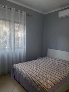 a bedroom with a bed and a window with curtains at Hidden Gem Vlora in Vlorë