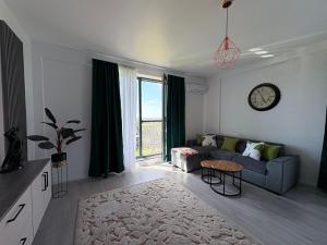 un salon avec un canapé et une horloge au mur dans l'établissement Relax Apartment Băile Felix, à Cordău