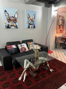 ein Wohnzimmer mit einem schwarzen Sofa und einem Glastisch in der Unterkunft Wiang Ping house in Chiang Mai