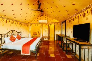 a bedroom with a bed and a flat screen tv at Udaipur Nature Valley Paradise -A Luxury stay in Mountains in Udaipur