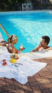 a man and a woman sitting in a pool with wine glasses at Domus Luxury villa Alassio in Alassio
