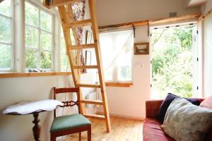 a tiny house with a ladder in a living room at Mormors Bakeri – B&B in Asarum