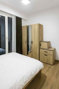 a bedroom with a white bed and wooden cabinets at Moonlight Panorama 27th Floor in Skopje