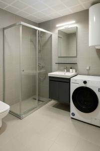 a bathroom with a shower and a washing machine at Moonlight Panorama 27th Floor in Skopje +4 photos