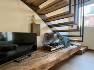 a living room with a table with a television and stairs at STH1 - Cachette en centre-ville in Saint-Hubert
