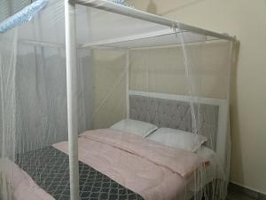 a bedroom with a canopy bed with pink sheets and pillows at MJ BRACHA Holiday Vacation Home in Mombasa