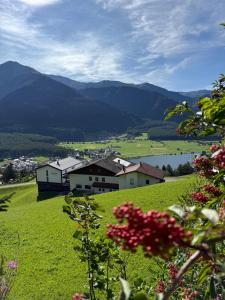 a green field with houses and a lake and mountains at Berghotel Plagött in San Valentino alla Muta