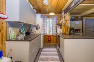 a kitchen with white counters and wooden ceilings at Savupirtti 1819 in Pudasjärvi