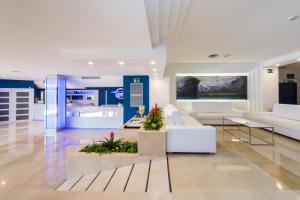 a living room with white furniture and a kitchen at Globales Mediterrani in Cala Blanca