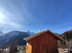 a wooden building with a mountain in the background at BATAJA - Dolomites Lodge in Valle di Cadore