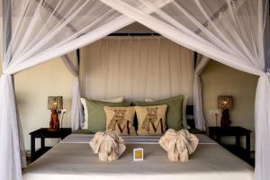 a bedroom with a canopy bed with two tables at Msandile River Lodge in Kakumbi