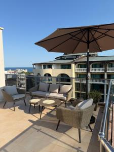 a patio with chairs and a table and an umbrella at Admiral Plaza Apartments in Sunny Beach