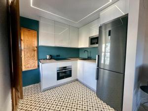 kuchnia z białymi szafkami i lodówką ze stali nierdzewnej w obiekcie Apartamento Calle Varela Centro w Grenadzie