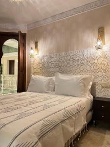 a bedroom with a large bed with white sheets at Riad Noon in Marrakesh