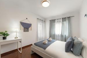 Un dormitorio blanco con una cama y un escritorio. en Papoa Beach House, en Peniche