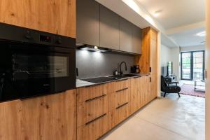 a kitchen with wooden cabinets and a black microwave at The Lake Break Apartamenty in Giżycko