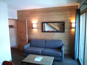 a living room with a blue couch and a mirror at apartment for 6 people in Béranger +2 photos