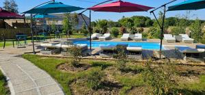 una piscina con sedie e ombrelloni accanto ad essa di Abaca Colors a Saint-Martin-de-Seignanx