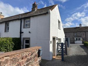 ein weißes Haus mit einer Ziegelwand davor in der Unterkunft Charming cosy cottage near the Lake District in Penrith