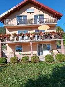 a building with a balcony with flowers on it at Guest House Toic in Korenica