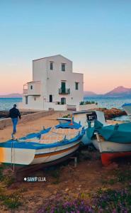 a group of boats sitting on the beach in front of a building at Casetta Bianca Luxury in Santa Flavia