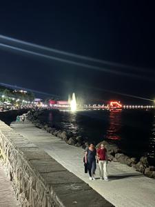 un uomo e una donna che camminano lungo un molo di notte di Судио Диксан a Pomorie