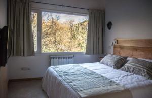 1 dormitorio con cama y ventana grande en Altos de la Montaña en San Martín de los Andes